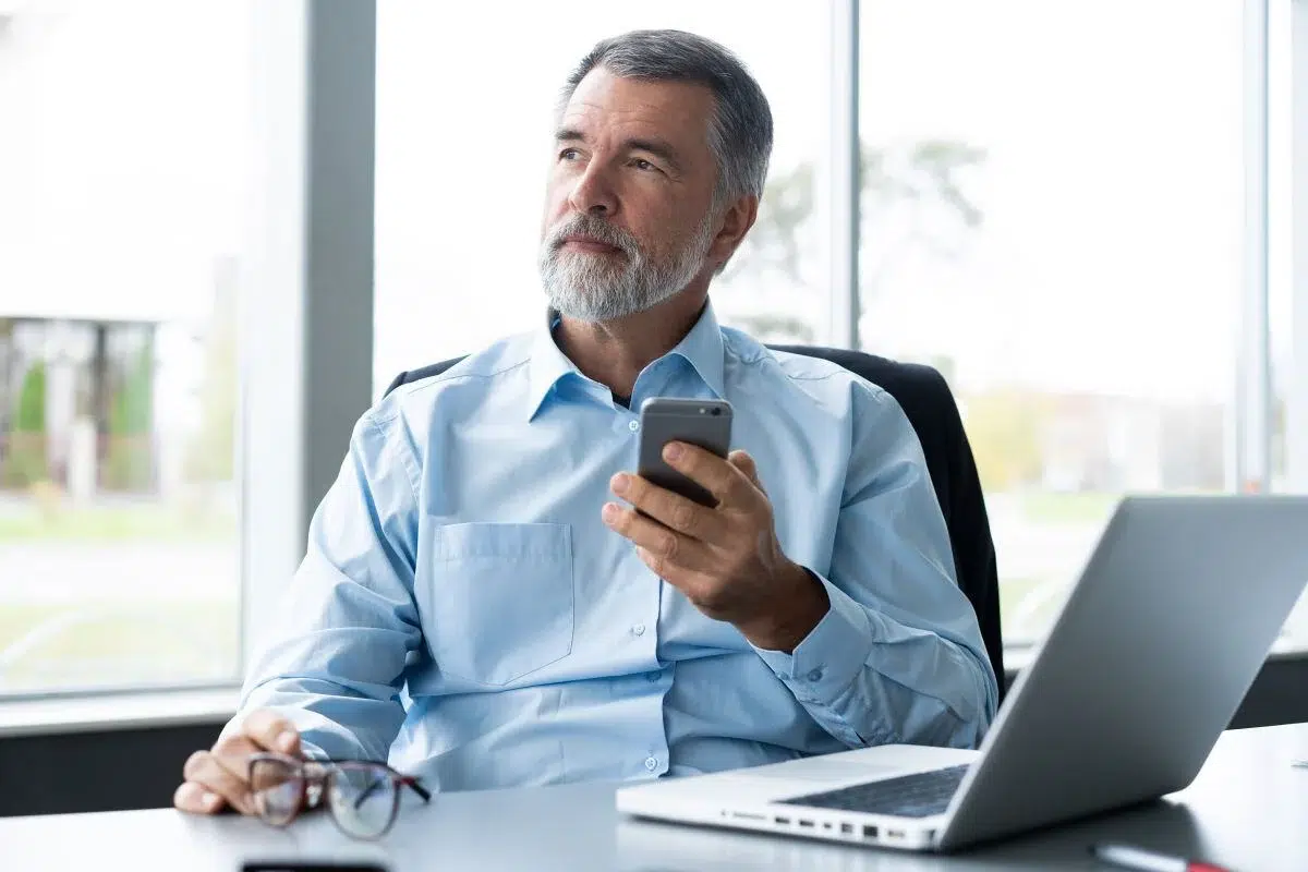 Business owner holding his phone and thinking